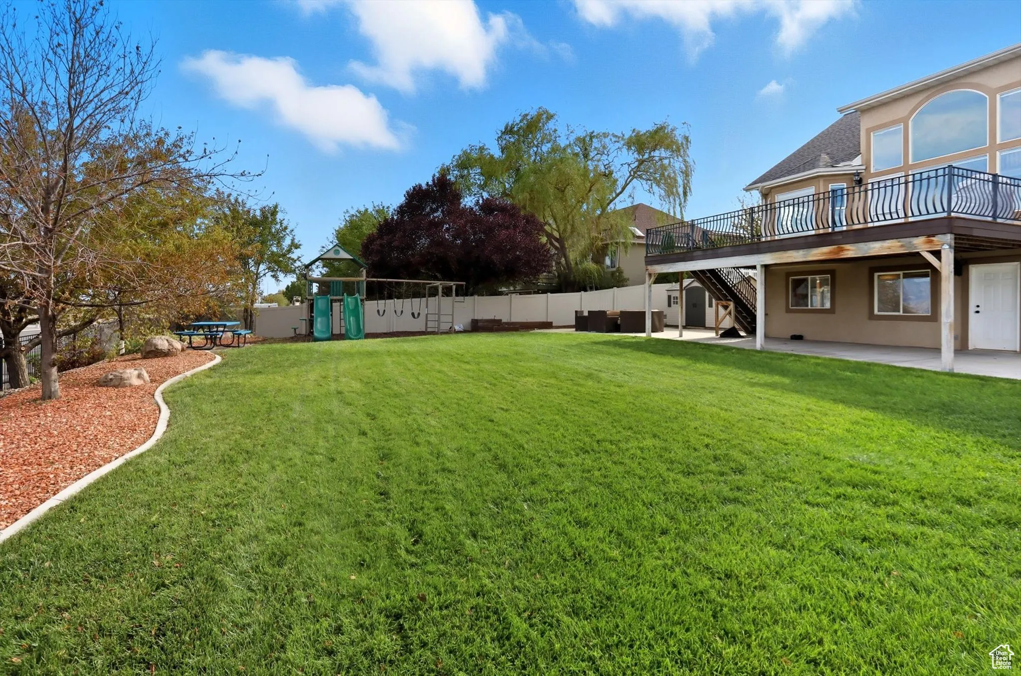 Fenced backyard with a patio area, a playground, stairway, and a deck