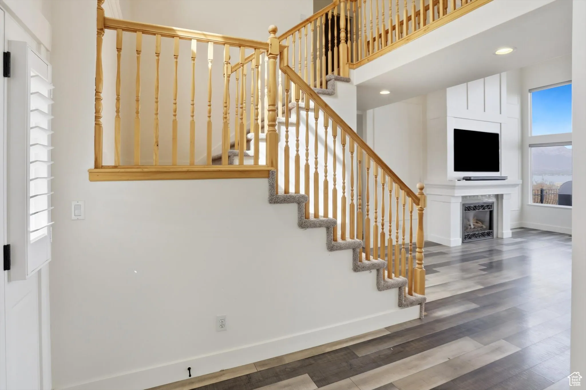 Staircase with a large fireplace, wood finished floors, a high ceiling, and recessed lighting