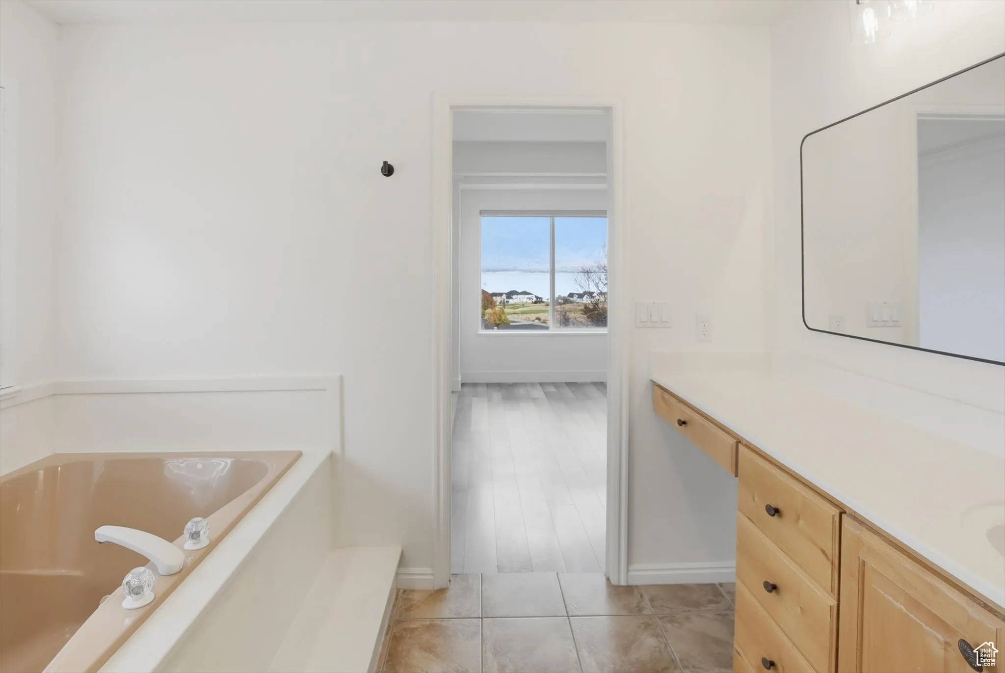 Bathroom with vanity, a garden tub, and light tile patterned floors