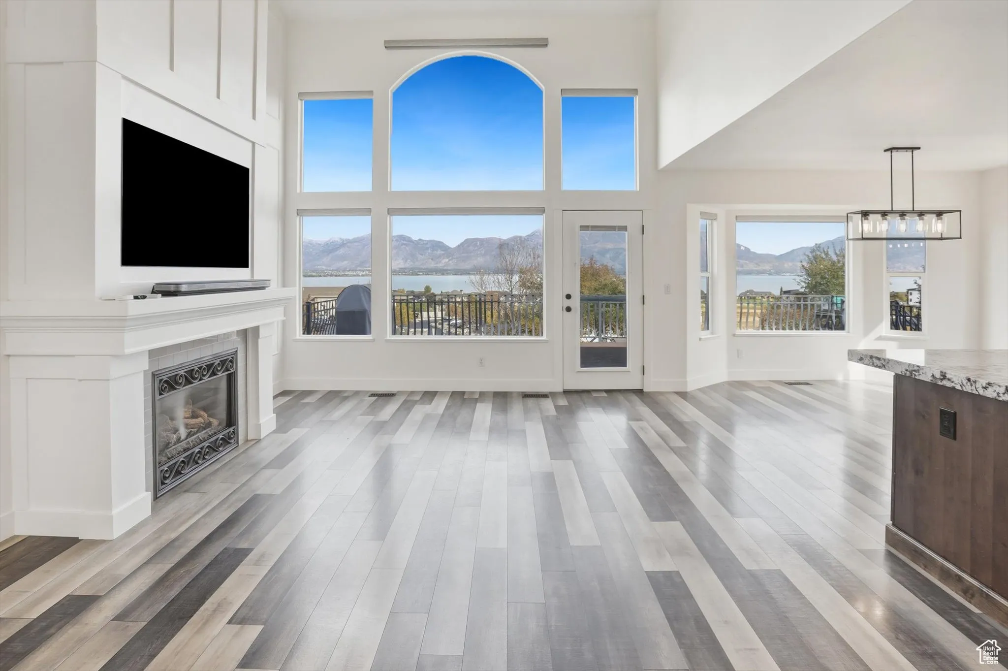 Unfurnished living room with a mountain view, a glass covered fireplace, a high ceiling, and light wood-style flooring