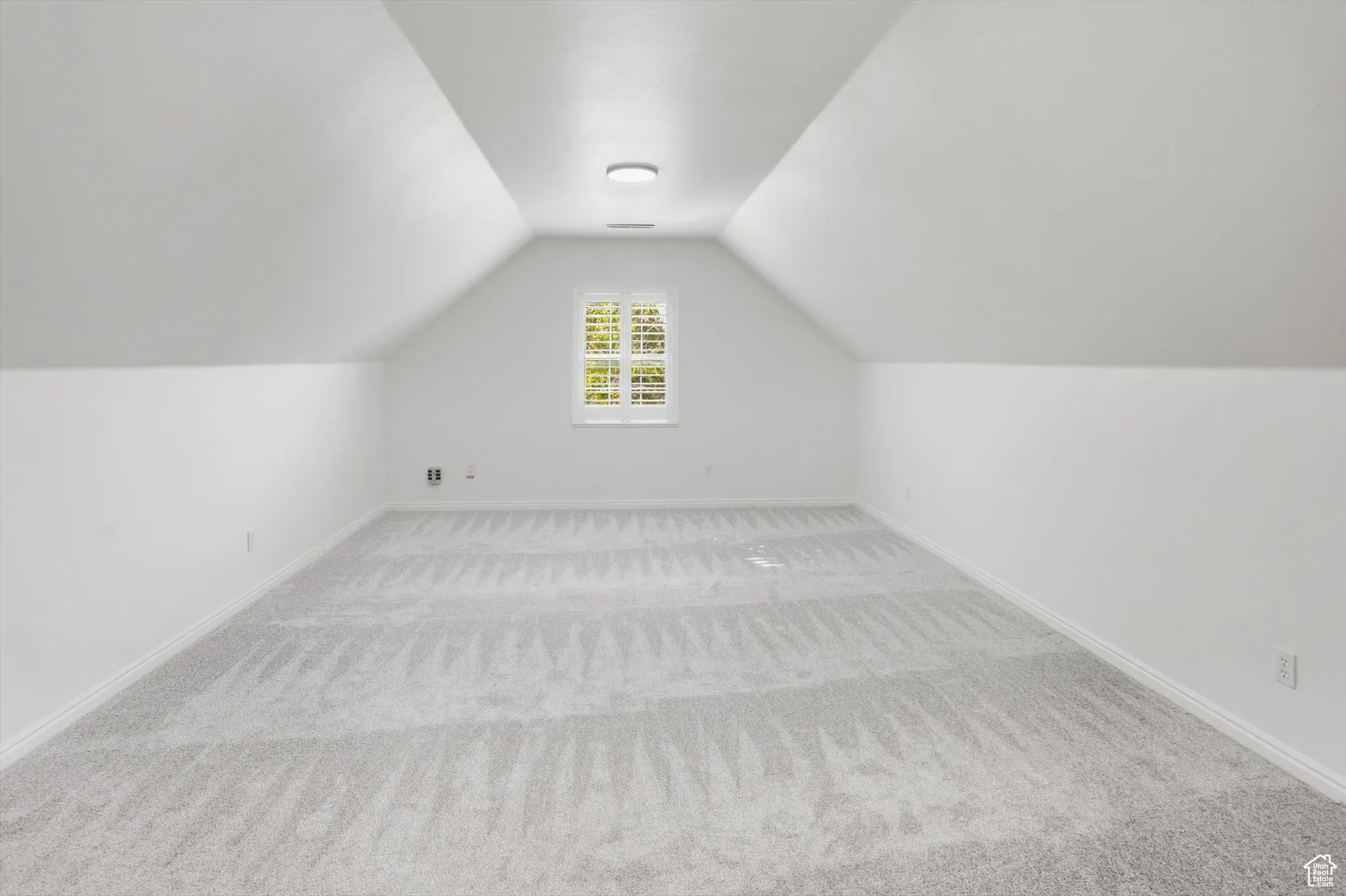 Additional living space with vaulted ceiling and carpet flooring