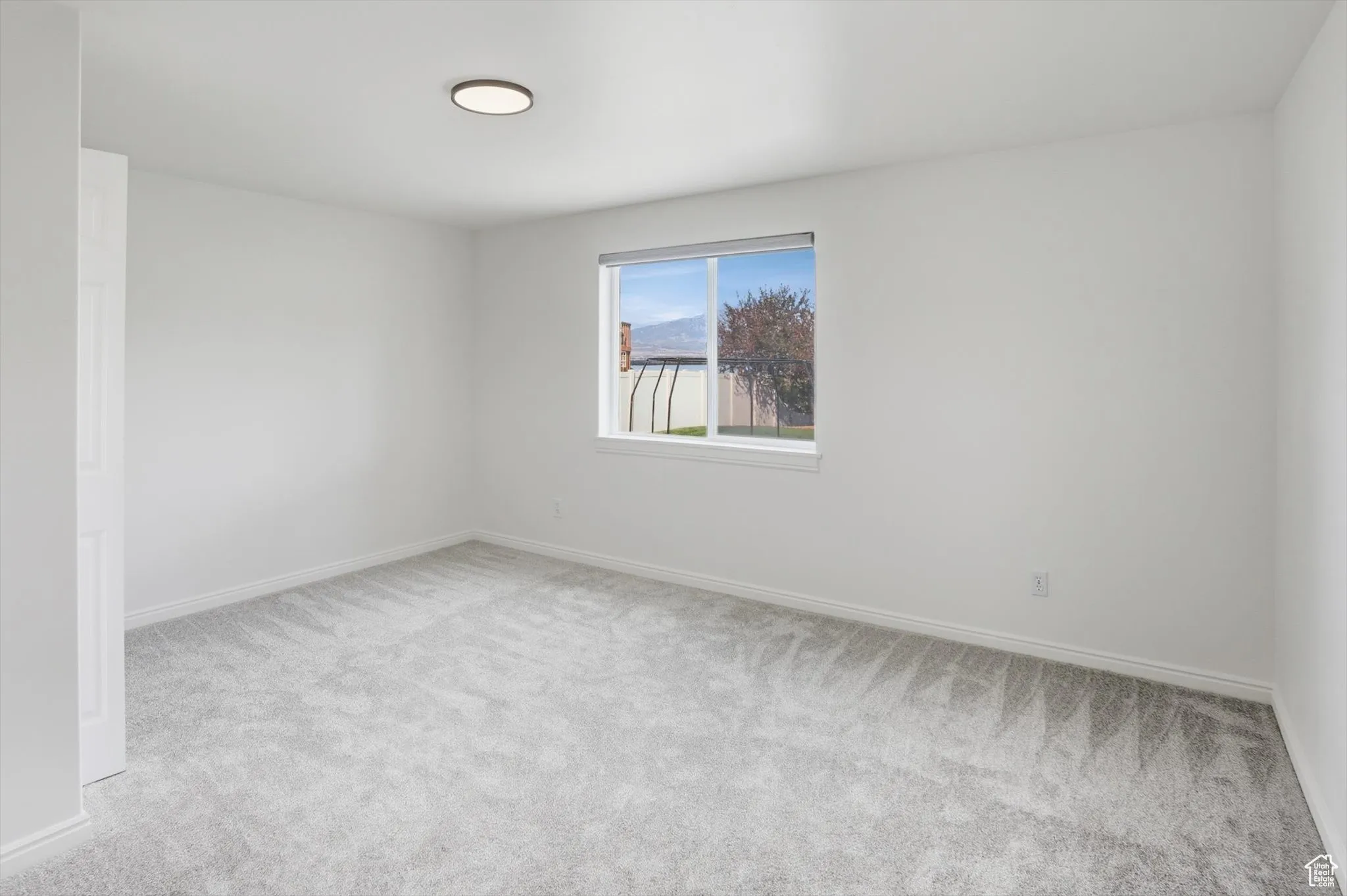Empty room featuring light colored carpet and baseboards