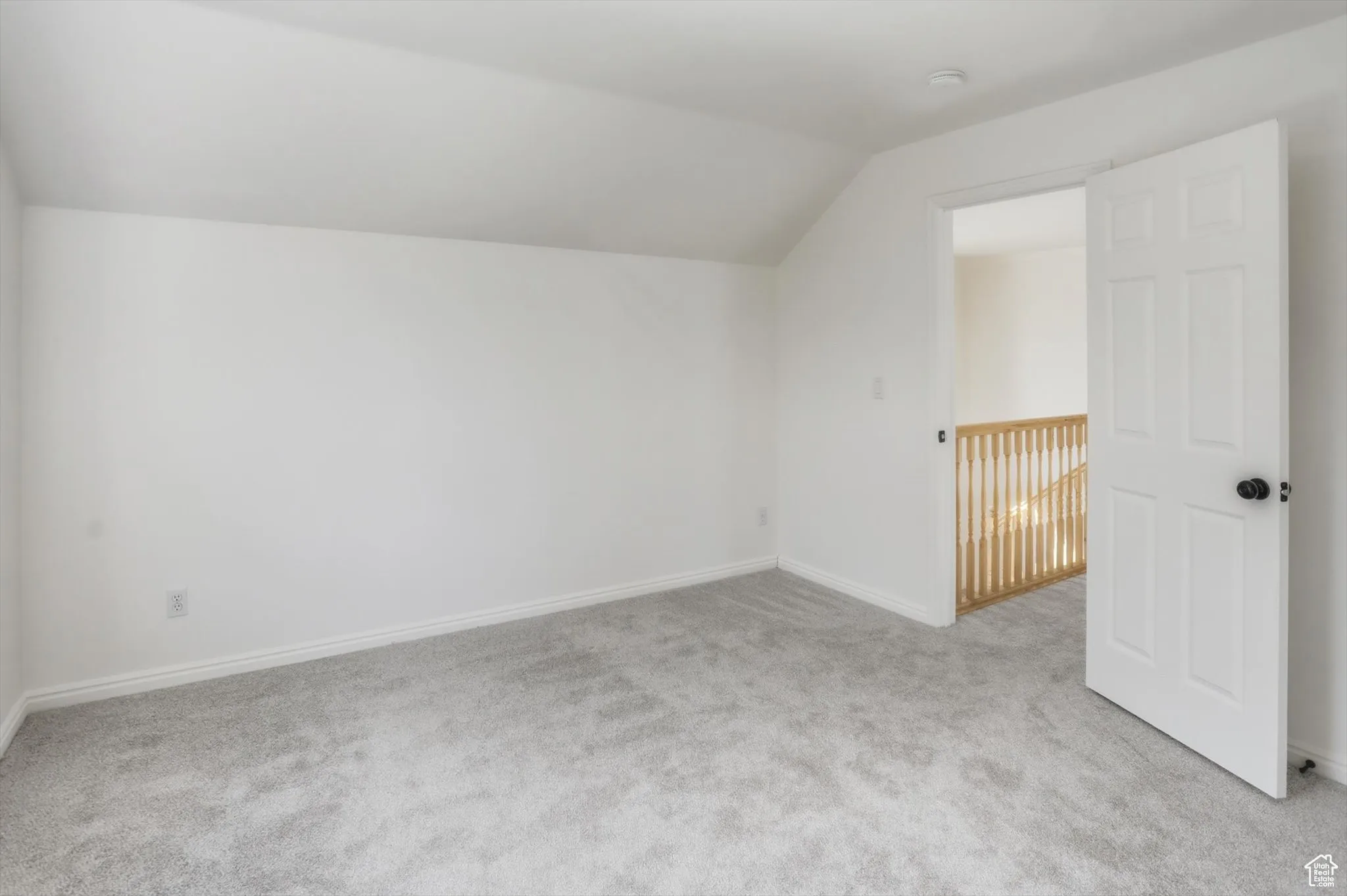 Additional living space featuring vaulted ceiling and light colored carpet
