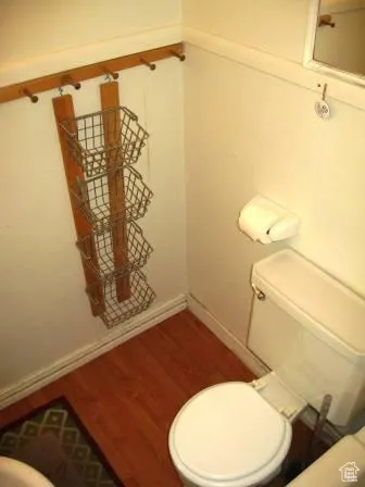 Half bathroom with toilet and wood finished floors