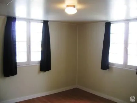 Empty room with baseboards and dark wood finished floors