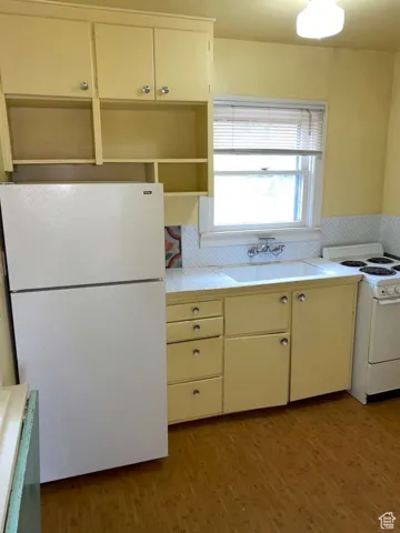 Kitchen with white appliances, tile counters, light wood finished floors, and white cabinets