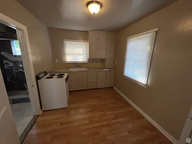Kitchen featuring light countertops, white range with electric cooktop, light wood-style floors, and white cabinetry