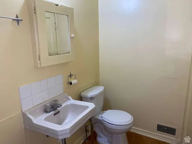 Half bathroom featuring toilet and wood finished floors