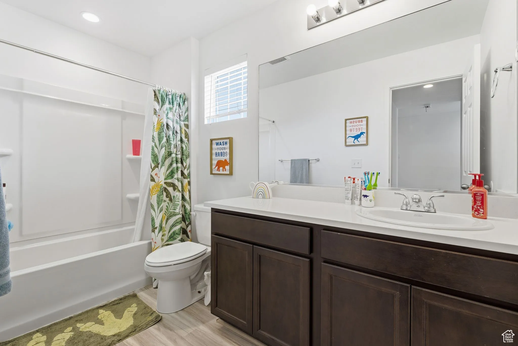 Full bathroom with double vanity, shower / tub combo with curtain, light wood-type flooring, and recessed lighting
