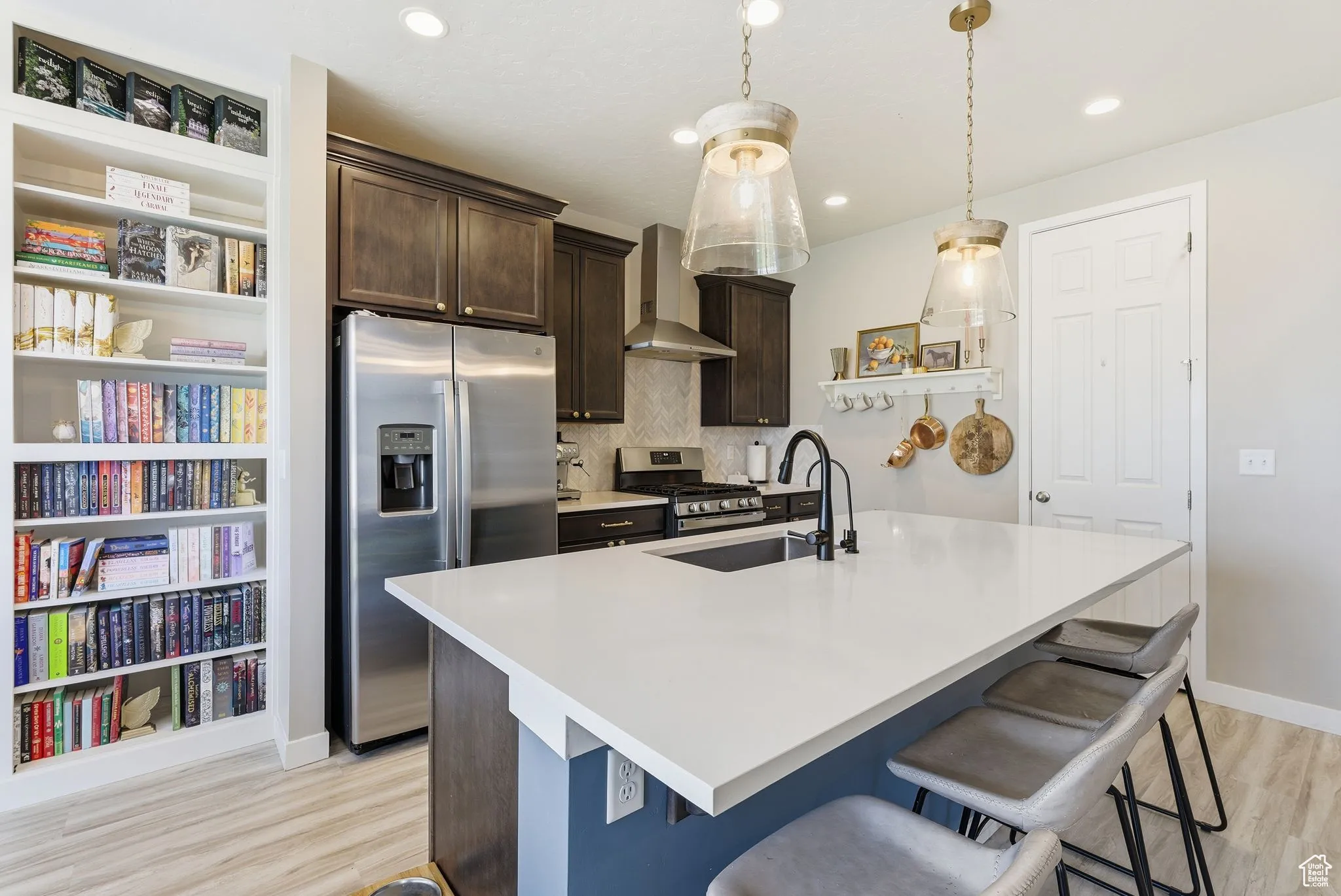 Kitchen featuring dark brown cabinets, stainless steel appliances, backsplash, a breakfast bar area, and an island with sink