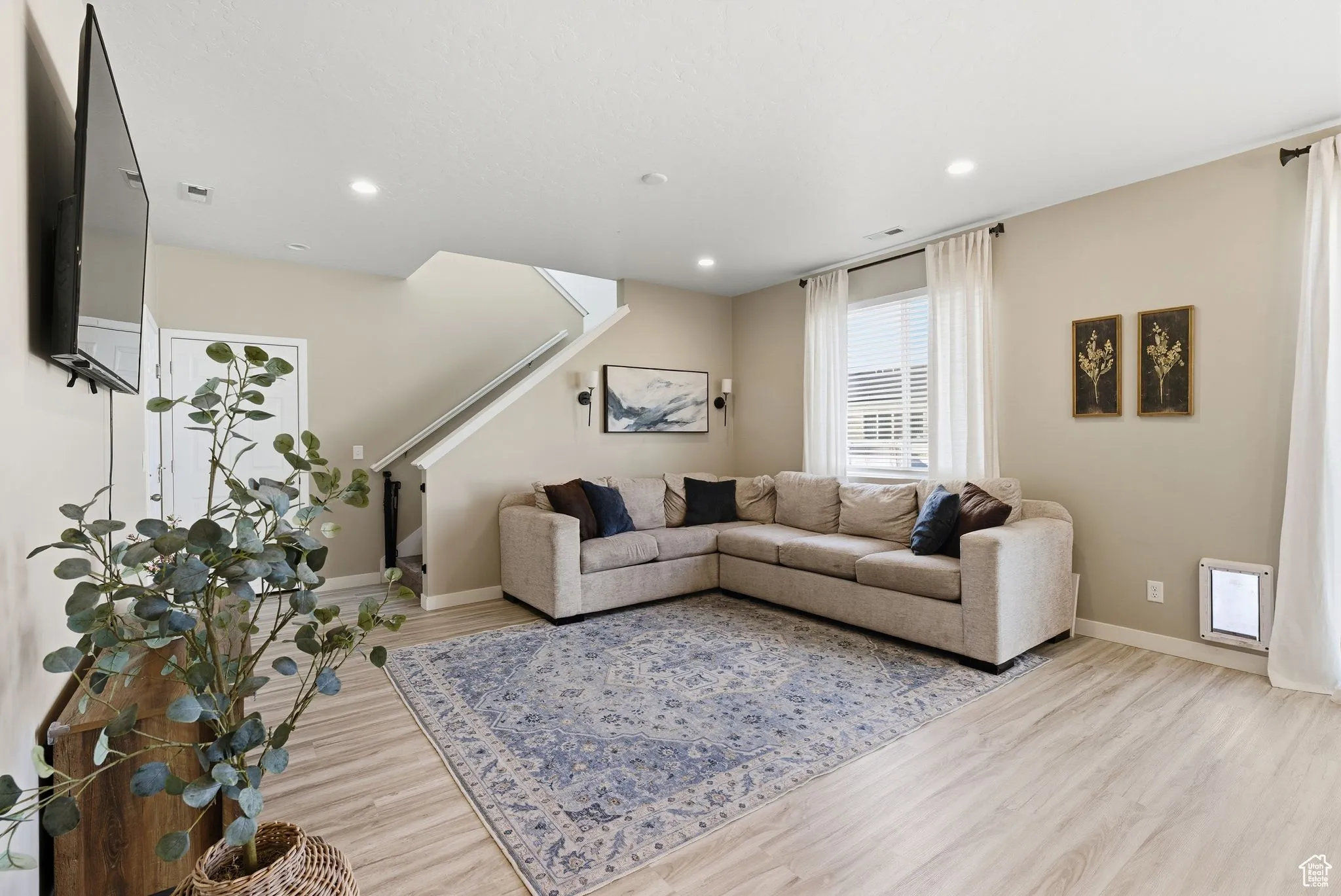 Living area with light wood-type flooring, recessed lighting, and stairs