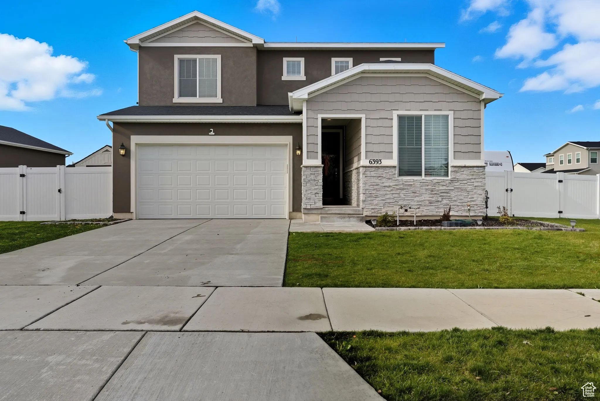 View of front of property featuring a gate, stone siding, concrete driveway, and a garage
