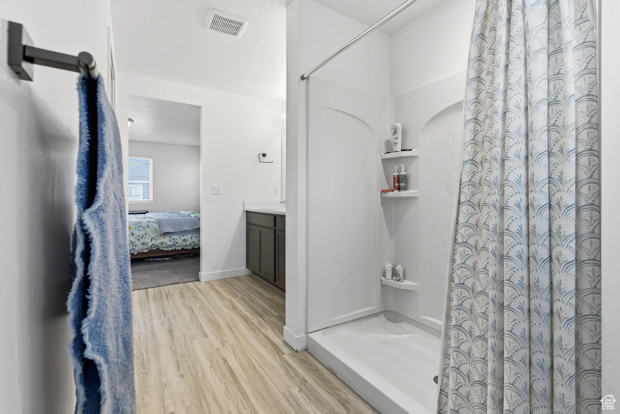 Ensuite bathroom with vanity, a shower stall, and light wood-type flooring