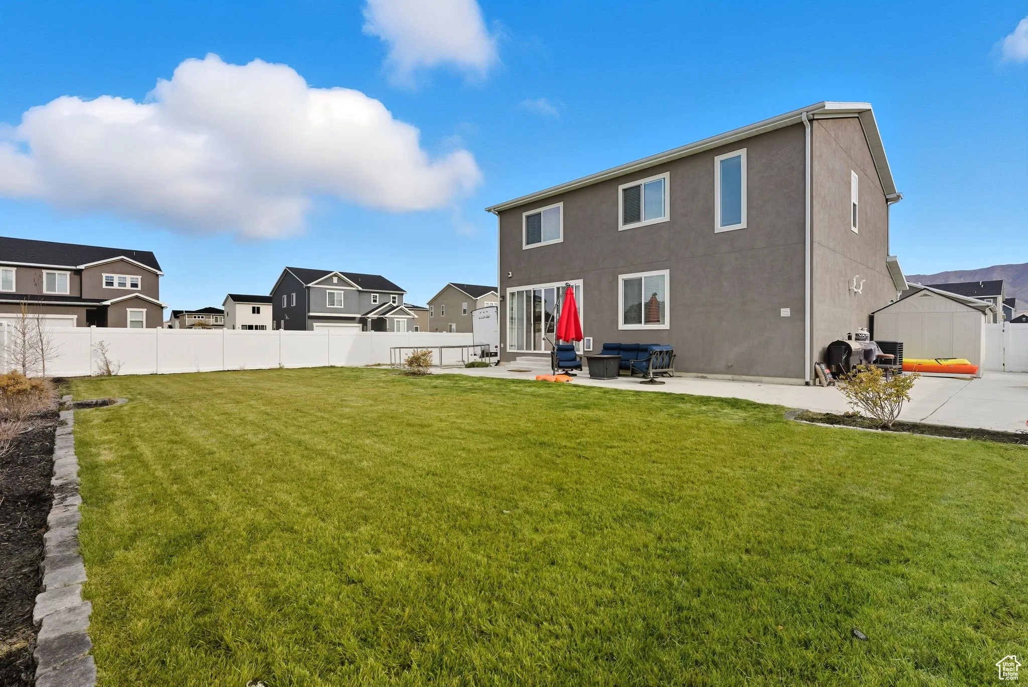 Back of house with a fenced backyard, a patio, a residential view, entry steps, and stucco siding