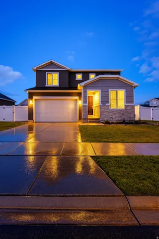 View of front of home with concrete driveway, stone siding, and an attached garage
