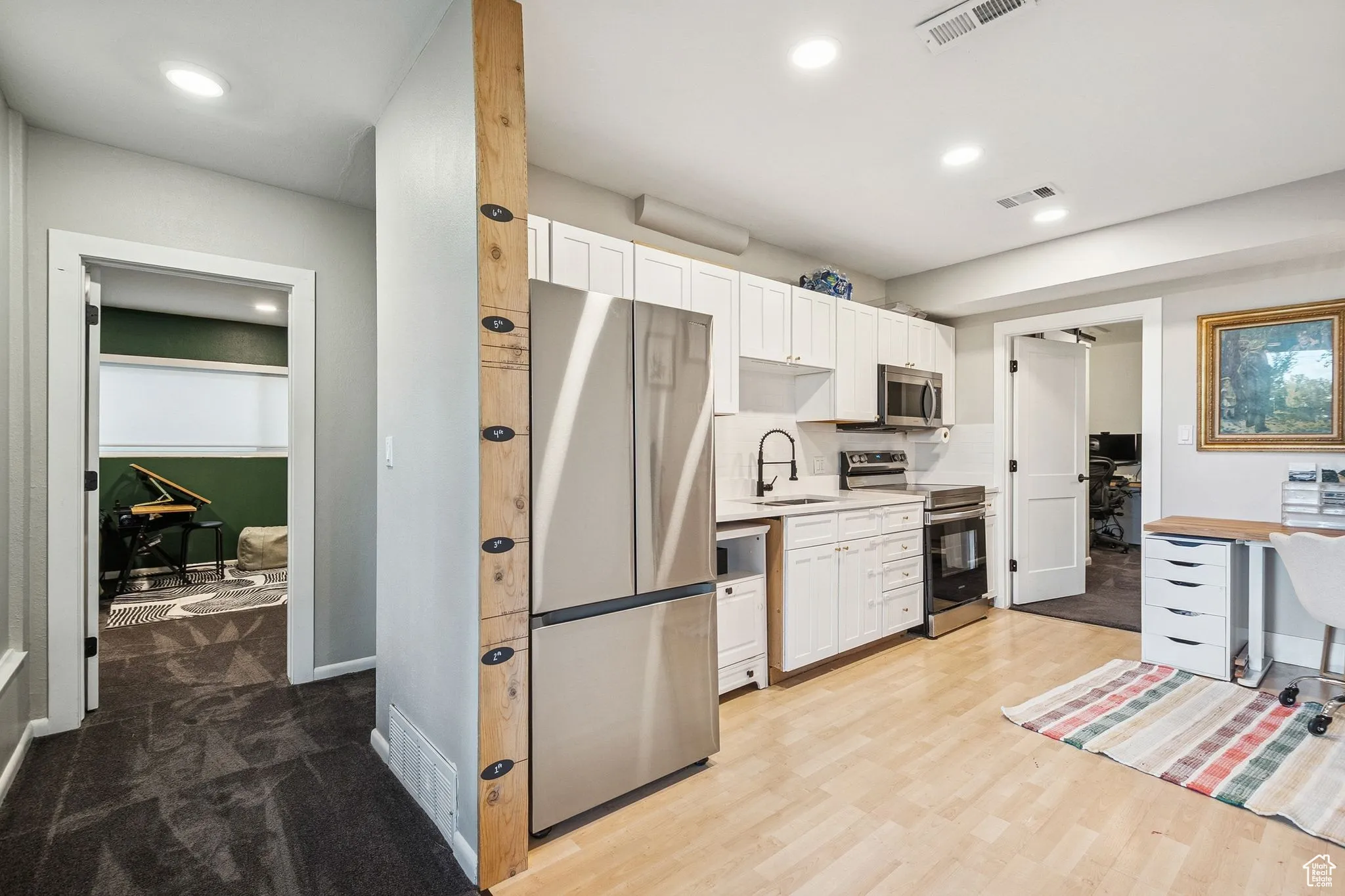 Kitchen with white cabinetry, appliances with stainless steel finishes, light countertops, decorative backsplash, and recessed lighting