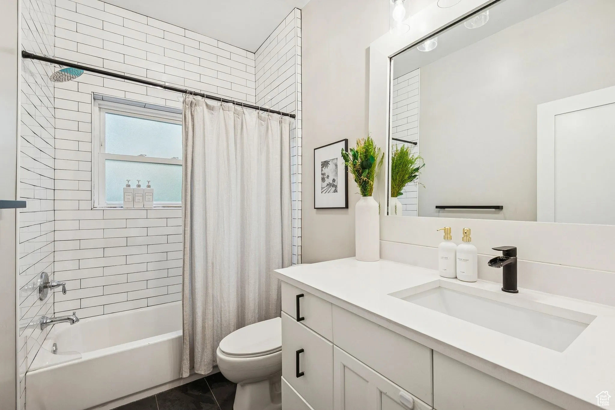 Full bathroom with shower / tub combo with curtain, vanity, and dark tile patterned flooring