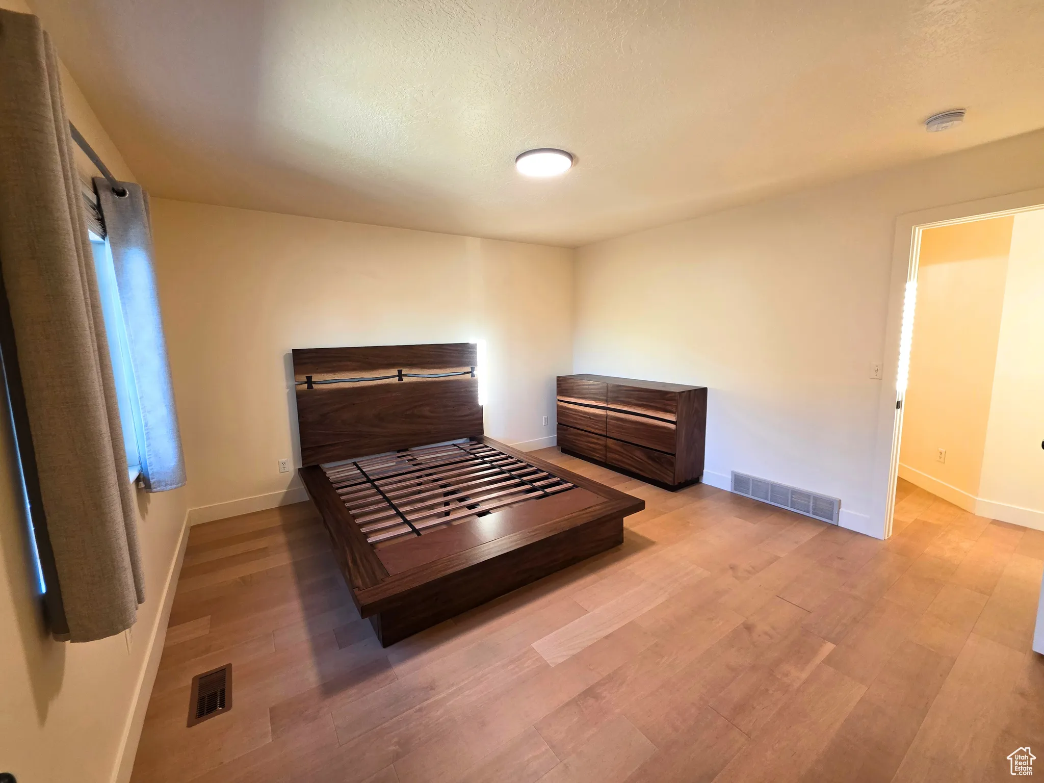 Bedroom with light wood finished floors and a textured ceiling