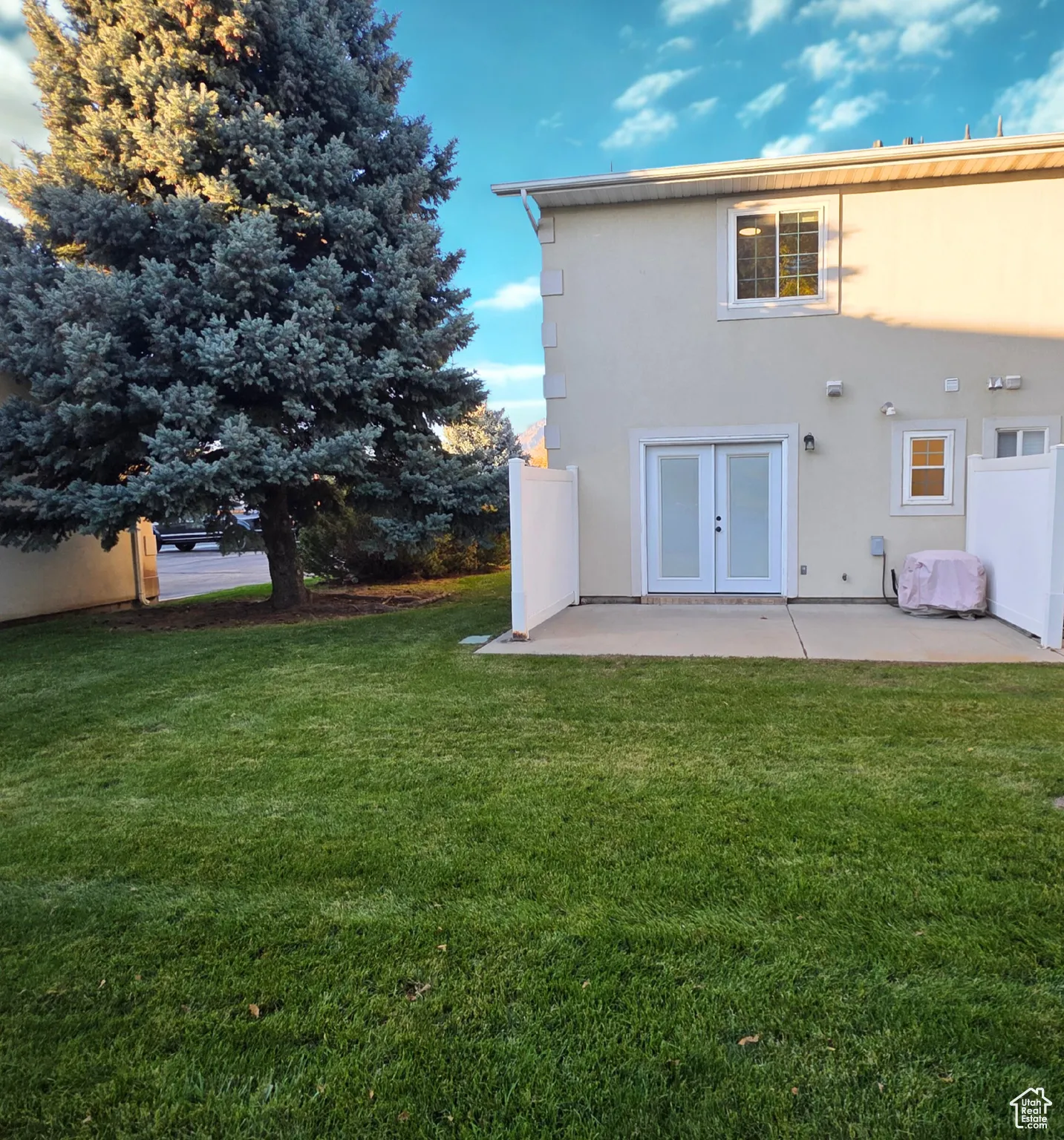 Back of property with a lawn, stucco siding, and a patio area