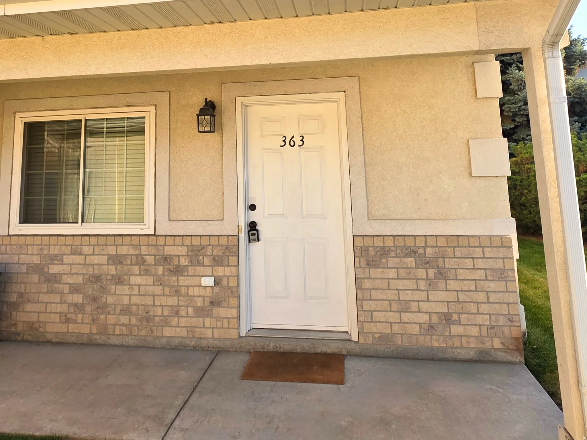Entrance to property with covered porch, stucco siding, and brick siding