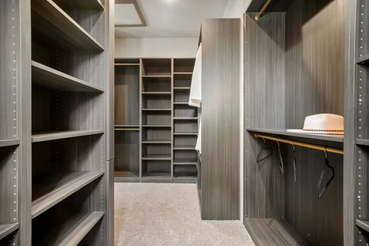 Custom closet system featuring wood-finish shelving, multiple hanging rods, and integrated storage solutions