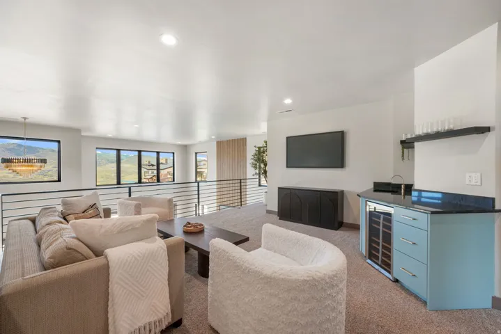 Spacious loft area featuring a built-in wet bar with a beverage cooler, dark countertop, and light blue cabinetry