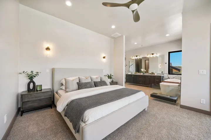 Spacious bedroom featuring light-toned walls, recessed lighting, and a modern ceiling fan