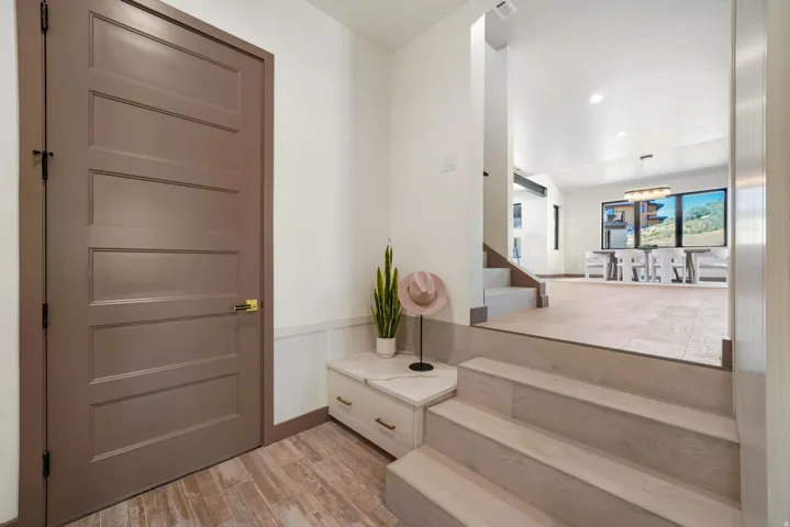 Entryway featuring wood-finish flooring, white wainscoting, and a multi-panel door with brass hardware