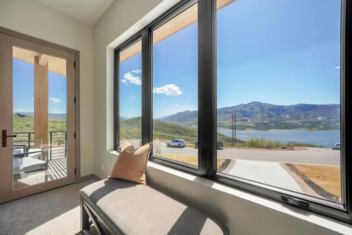 Expansive window wall with black frames and a large glass door opening to a private balcony
