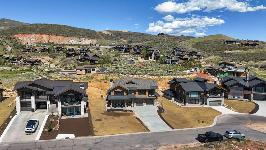 Contemporary mountain-style residence featuring a dark-toned exterior with expansive windows, two prominent balconies, and a two-car garage