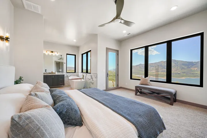 Spacious room featuring multiple large windows, a freestanding soaking tub, dual vanity, and a ceiling fan