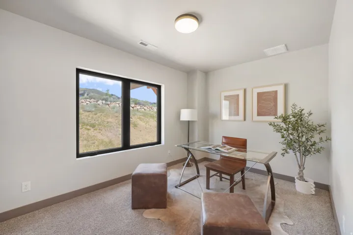Room featuring a large black-framed window, neutral wall paint, gray carpeting, a single ceiling light fixture, and gray baseboards