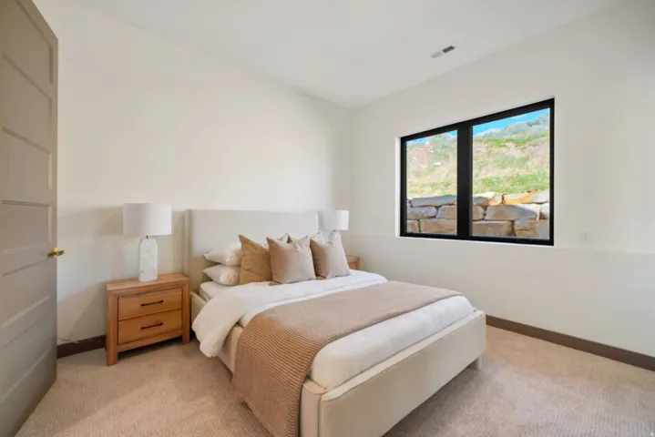 Carpeted bedroom featuring a large window with black trim, a paneled interior door, and light-toned walls