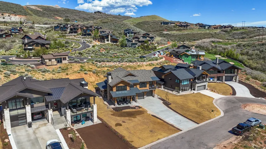 Contemporary mountain-style architecture featuring multiple pitched roofs, extensive window placements, stone accents, and integrated garages