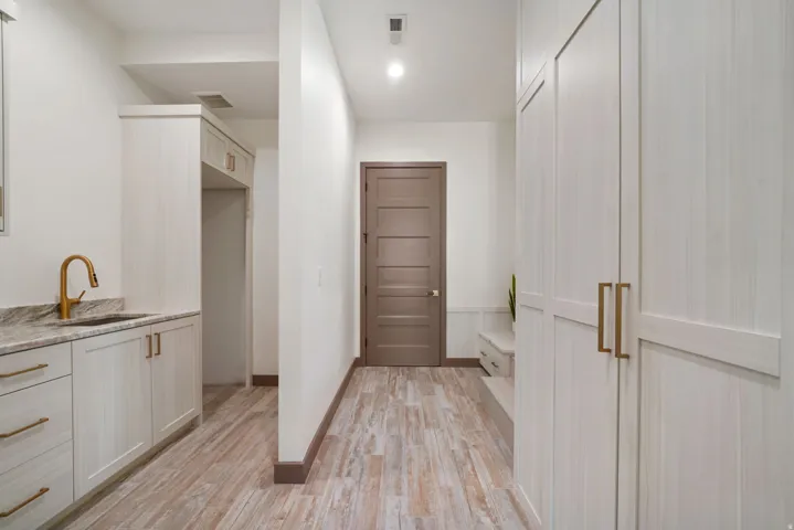 Functional utility area featuring extensive cabinetry with brass-finish hardware