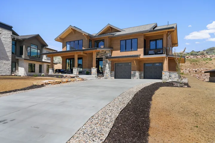 Contemporary architecture featuring wood paneling, stone accents, and a multi-car garage