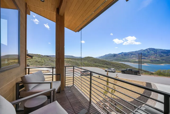 Covered balcony featuring a wood-finish ceiling, horizontal railing system, and a scenic mountain and lake backdrop