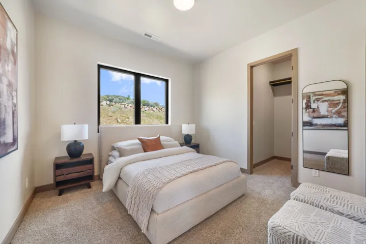Bedroom featuring large horizontal windows with black framing, neutral-toned walls, and plush carpeting