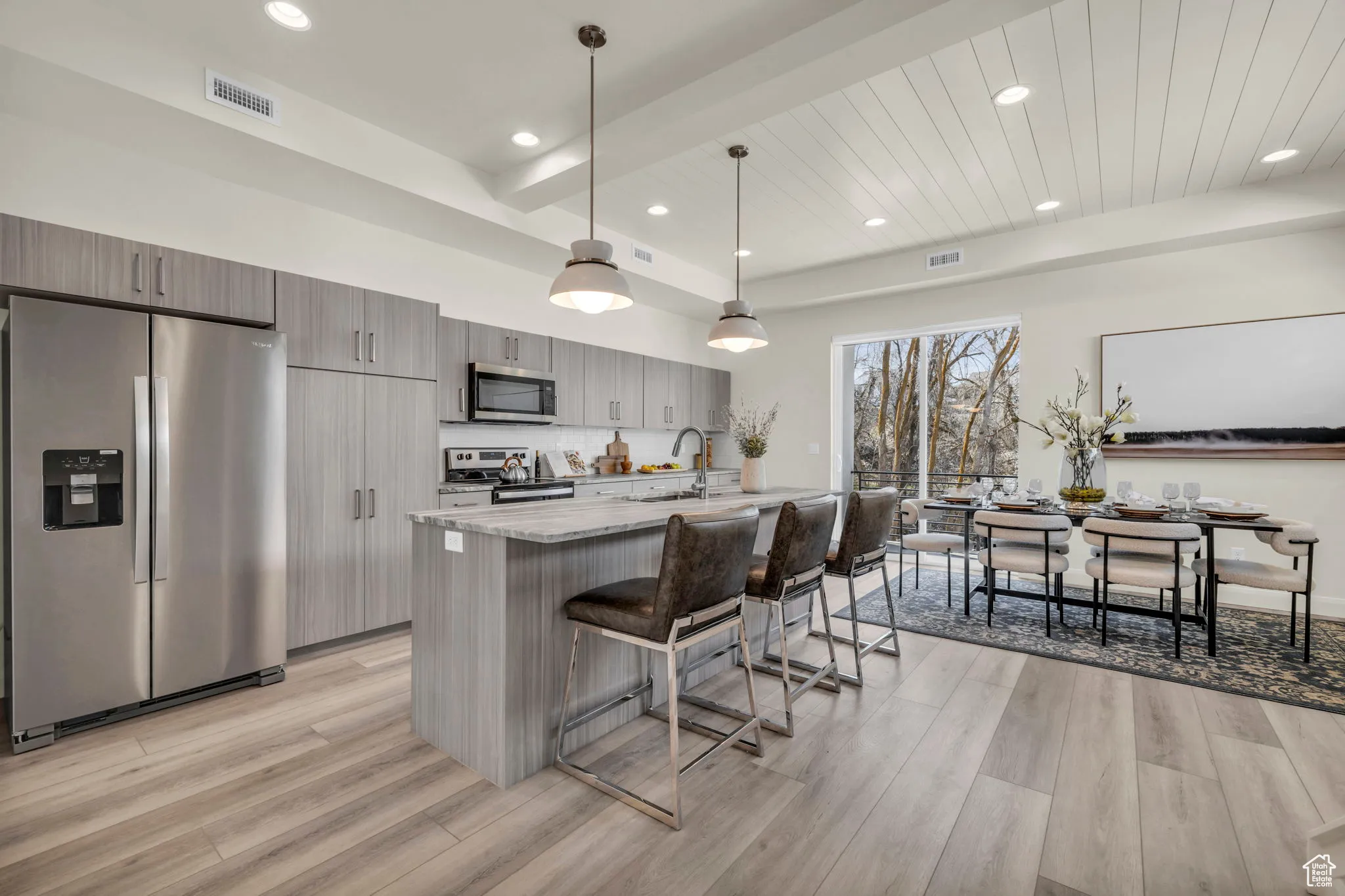 Kitchen with stainless steel appliances, a kitchen bar, decorative light fixtures, a center island with sink, and recessed lighting