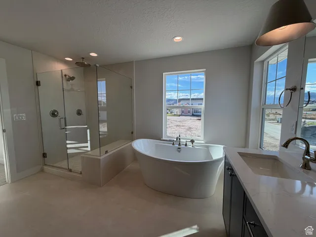 Bathroom with a soaking tub, a stall shower, a textured ceiling, vanity, and recessed lighting