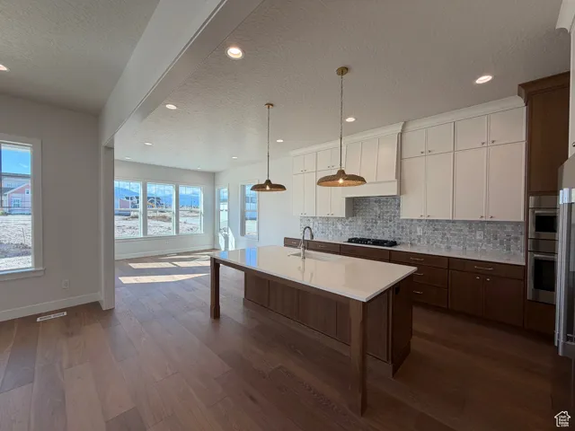 Kitchen featuring a textured ceiling, white cabinetry, dark brown cabinetry, tasteful backsplash, and dark wood finished floors