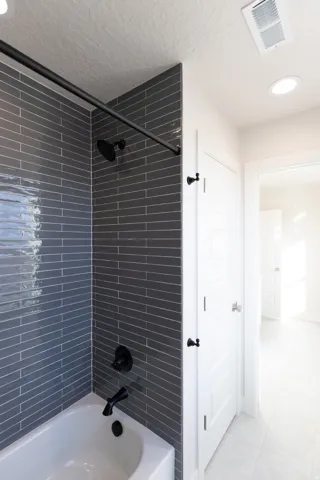 Bathroom featuring shower / tub combination, recessed lighting, a textured ceiling, and light tile patterned floors
