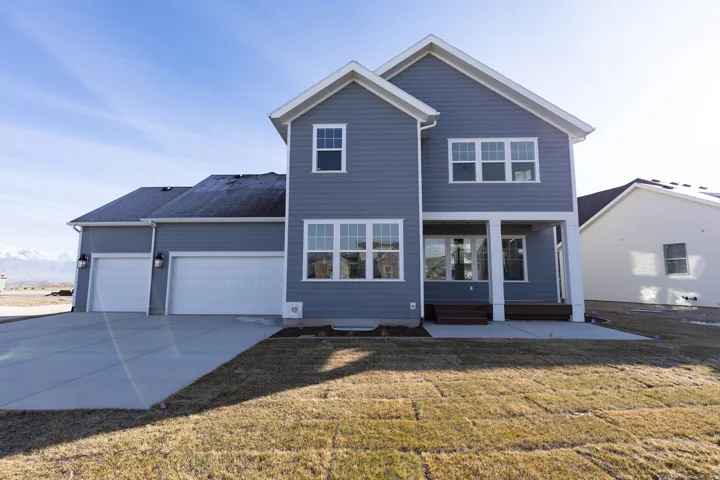 View of front facade featuring a patio, a garage, a front lawn, concrete driveway, and a mountain view