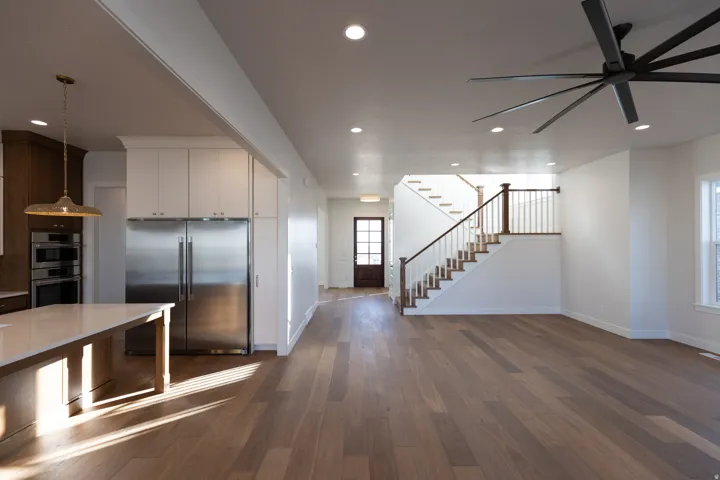 Kitchen featuring stainless steel appliances, dark wood-style flooring, hanging light fixtures, open floor plan, and white cabinetry