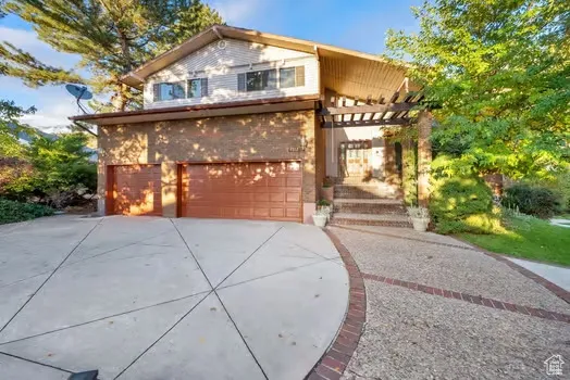 View of front of home with driveway, brick siding, and an attached garage