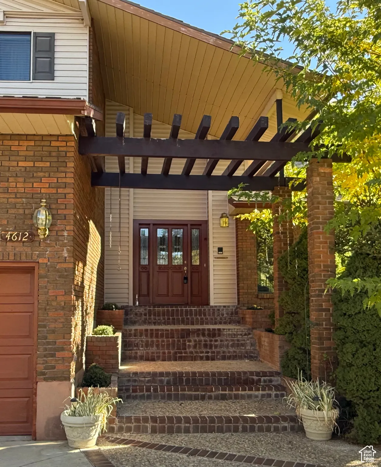 Beautiful shaded front door entry featuring brick stairs and built-in flower planters