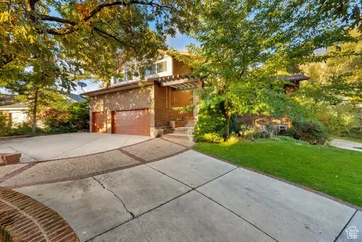 View of front of property featuring a front yard, driveway, a garage, and stucco siding
