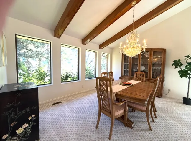 Dining area featuring lofted ceiling, hanging lights, and light carpet