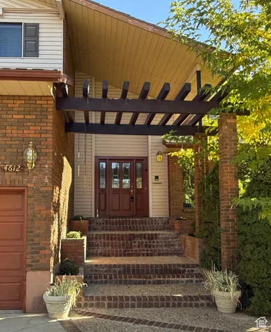 Beautiful shaded front door entry featuring brick stairs and built-in flower planters