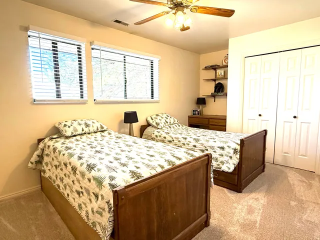 Bedroom with light carpet, ceiling fan, Double-wide closet & built-in desk
